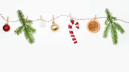 christmas ornament, spruce twigs, orange, candy cane and snowflake on clothespins on a light backgroundの写真素材