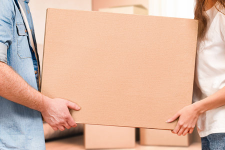 a man and a woman carry a cardboard box in their hands, moving to a new home