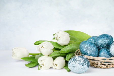 white tulips and a plate with blue easter eggsの写真素材