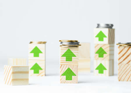 wooden cubes with coins and painted green upward arrows, the concept of growth and rise on a light gray background, the concept of profit growthの写真素材