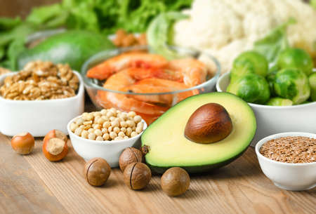 avocados, nuts, soybeans, flax seeds, Brussels sprouts and cauliflower, shrimp and spinach on a wooden backgroundの写真素材