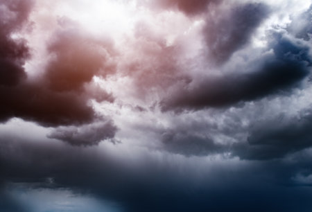 background of dark storm clouds and the rays of the sun breaking through the cloudsの写真素材