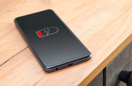 smartphone on the table. phone with low charged battery screenの写真素材