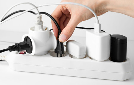 hand connects an electric plug to an extension cord