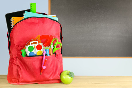 school backpack and apple in the classroom on the background of Chalkboardの写真素材