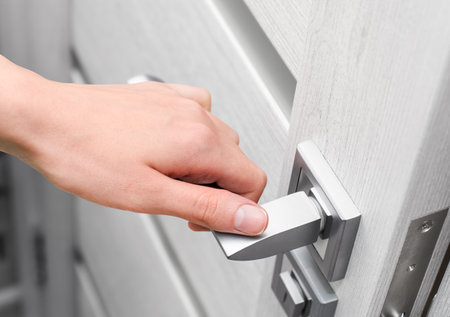 woman's hand holding on to the handle of an interior door, opening itの写真素材