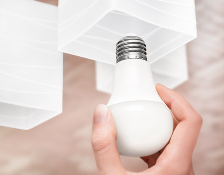 woman screwing a light bulb into a ceiling lamp close-upの写真素材