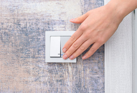 woman's hand touches the light switch on the wallの写真素材