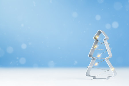 one glowing cookie cutter in the shape of a Christmas tree on a blue backgroundの写真素材