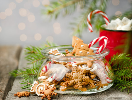 ginger cookies in a jar, sweets, a mug of cocoa and fir branches on a wooden tableの写真素材