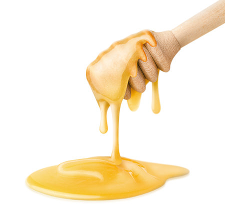 honey dipper with honey dripping into pile, isolated on white backgroundの写真素材