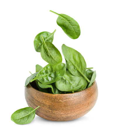 wooden plate with falling spinach leaves on a white isolated backgroundの写真素材