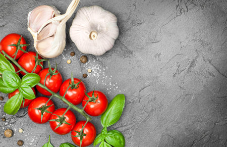 Cherry tomatoes, garlic, basil and spices on a concrete background, top viewの写真素材