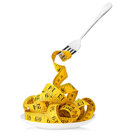 yellow sewing measuring tape wound onto a fork on a white isolated background. weight loss and diet conceptの写真素材