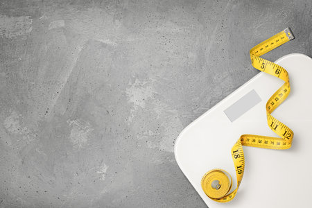 scales and measuring tape on a gray background. diet and weight loss conceptの写真素材