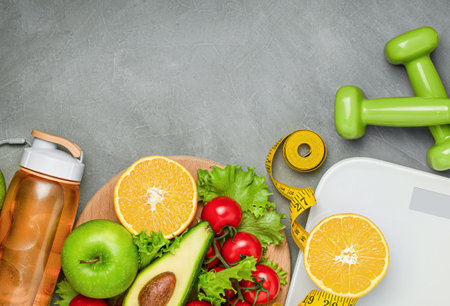 fresh vegetables and fruits, scales, dumbbells, centimeter and water bottle on a gray concrete backgroundの写真素材