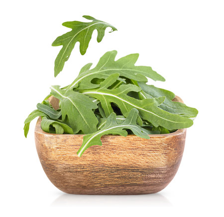 arugula in a wooden plate on an isolated white backgroundの写真素材