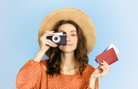 happy female tourist with camera and passport with tickets in hands on blue backgroundの写真素材