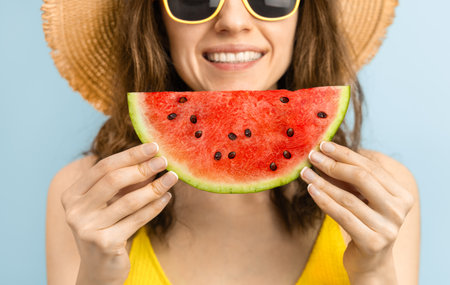 happy woman in beach hat smiling and holding watermelon slice close-upの写真素材