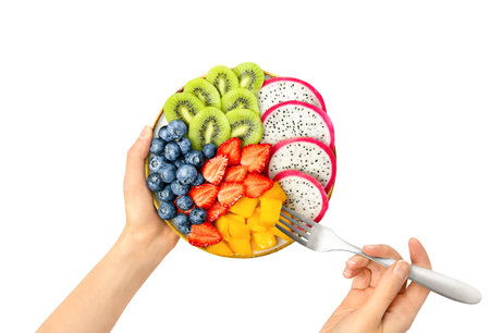plate with sliced ââfruits and berries in the hands of a woman, top view, on a white isolated backgroundの写真素材