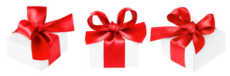 three white gift boxes with red bows at different angles on a white isolated backgroundの写真素材