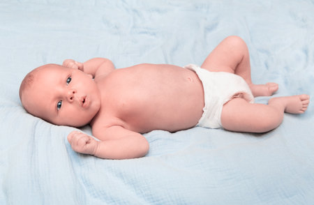 newborn baby in diaper lying on bedの写真素材