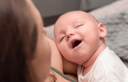 sleeping baby in mother's arms smiling in sleep, close-upの写真素材