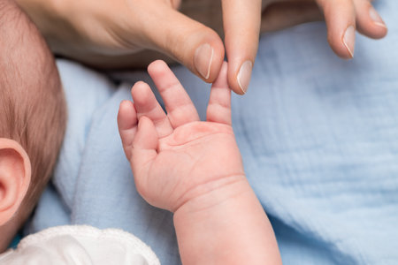mother holding baby by finger on hand close-upの写真素材