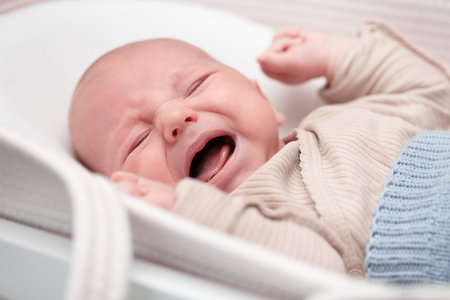 newborn baby cries loudly lying in cradleの写真素材