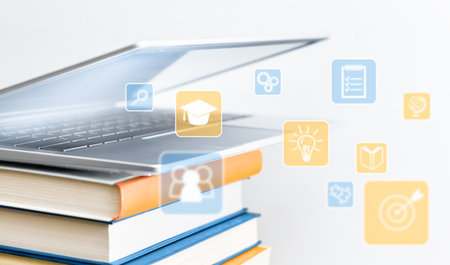 half-open laptop on a stack of books with education iconsの写真素材