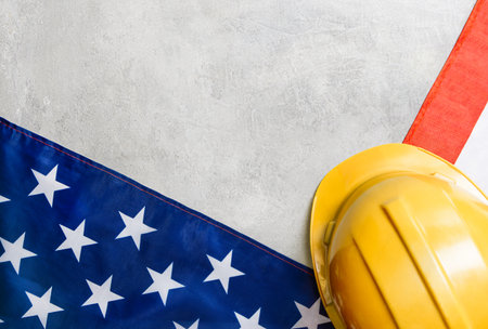 Construction worker helmet and American flag on gray concrete background. labor day conceptの写真素材