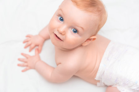 cute smiling seven month old baby in diaper close up, top view