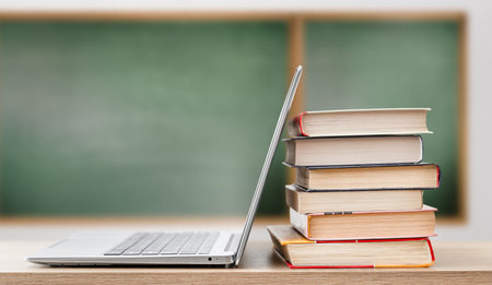 open laptop and stack of books on blackboard background. education conceptの写真素材