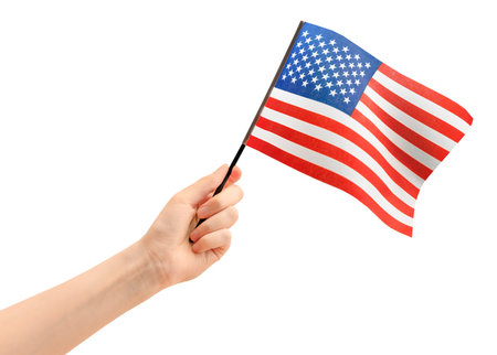 female hand holding small American flag on white isolated backgroundの写真素材