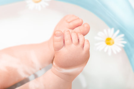 baby feet in bath with chamomile, close up. baby care conceptの写真素材