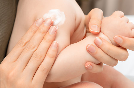Women's hands apply cream to a baby's bodyの写真素材