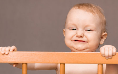 a funny baby standing in a cribの写真素材