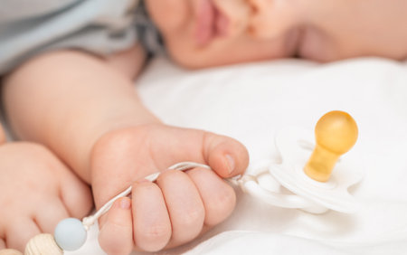 the baby is sleeping and holding a pacifier in his handの写真素材