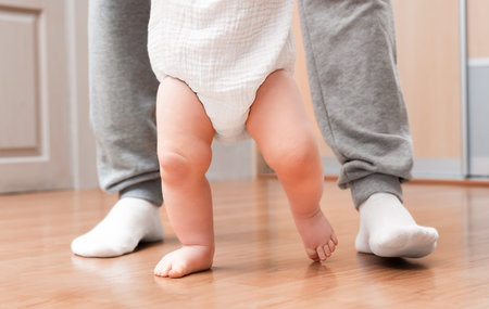 The baby takes his first steps with his father's support
