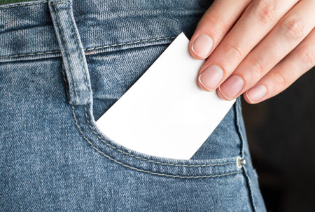 A woman's hand takes out a blank business card from her jeans pocketの写真素材