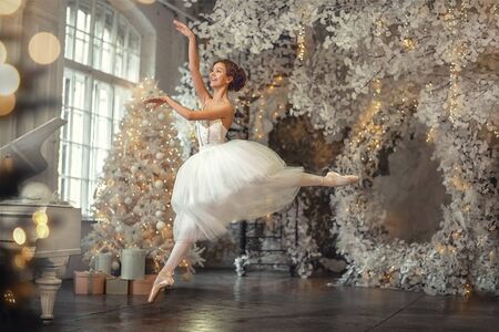 young beautiful russian girl dancing in pointes near the christmas treeの写真素材