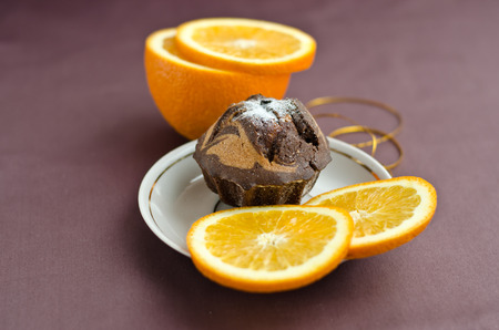 Chocolate cake, sliced ââorange on the plate and gold ribbon on the table.の写真素材