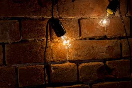 Incandescent lamp hanging on grunge brick wallの写真素材