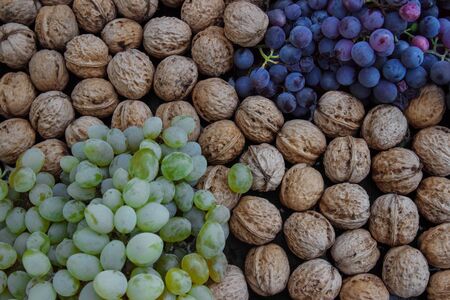 Brushes of green, white and purple grapes lying on the kitchen table with walnuts close-up top viewの写真素材