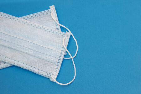 Two medical disposable masks on a blue background with free space for text top viewの写真素材