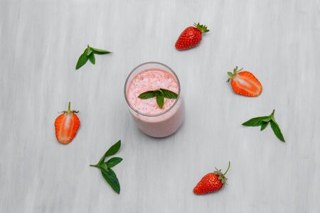 Milkshake with fiber and green mint leaves and strawberry berries whole and cut on a white wooden background top viewの写真素材