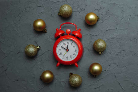 Red clock with gold Christmas toys matte and shiny on a gray vintage putty background top view, close-up, flat composition, concept of waiting for Christmas, New year, Christmas eve, home decorationの写真素材