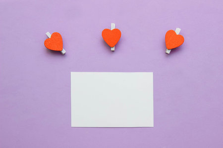 White paper card with three clothespins with red hearts on pink background with empty space for close-up text, greeting card template concept, note layout, Valentine's Day, Birthday and Mother's Dayの写真素材