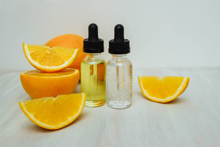 Two glass cosmetic bottles with oil and serum with pipettes on a white background with orange slices close-up, beauty concept, Skin care and treatment, aromatherapy, rejuvenation and massage, acneの写真素材
