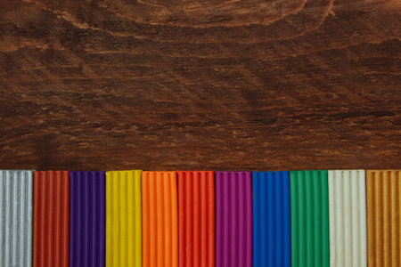 Multi-colored plasticine, close-up of plasticine modeling on brown wooden background with empty space for text, concept of children's creativity, fine motor skills, back to school, templateの写真素材